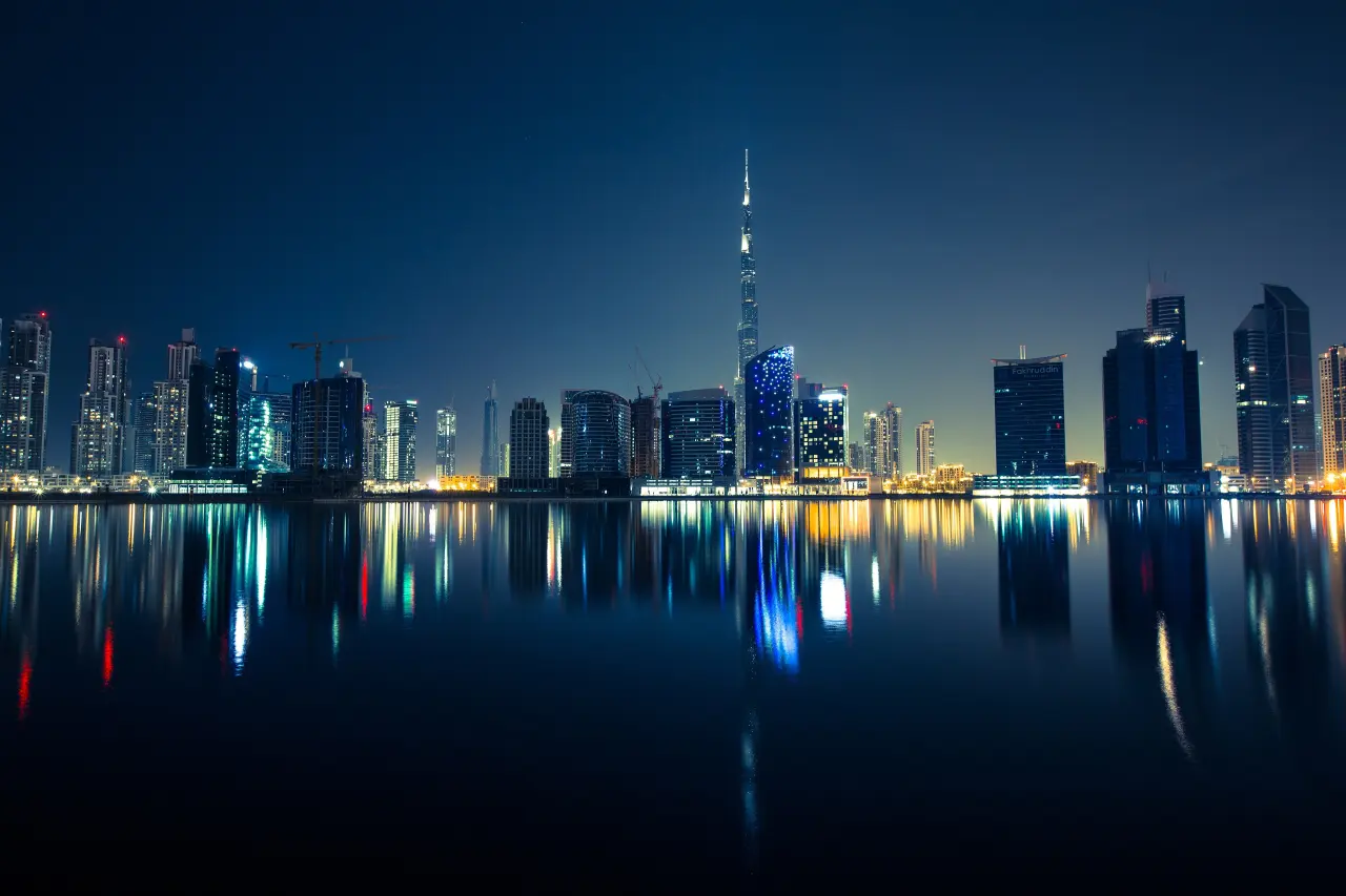 Dubai skyline with Burj Khalifa reflected on water at night